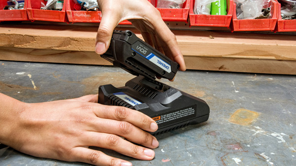 Close up of hands placing Li-ion battery onto charger.
