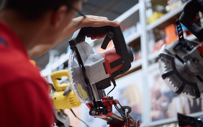 Man looking at circular saw with safety guard in store.