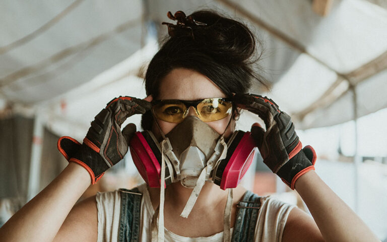 Woman wearing respirator, safety glasses, and gloves to protect from silica.