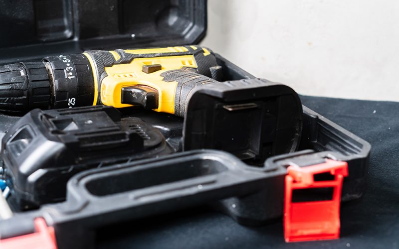 Transporting yellow cordless drill in case with battery.
